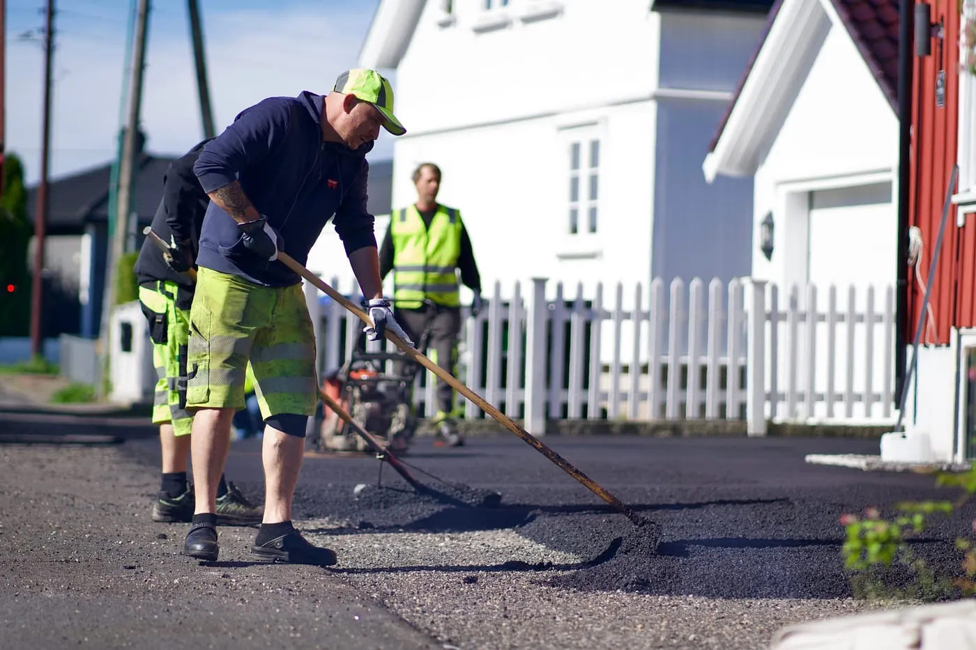 Asfaltarbeidere raker ut asfalt i en innkjørsel